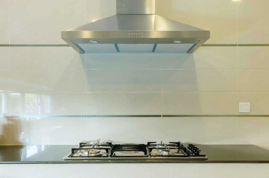 Wall Hood Over Gas, San Mateo — Wall-mounted stainless hood hung inside the manufacturer's height range over a gas cooktop, anchored into blocking and balanced at every speed.