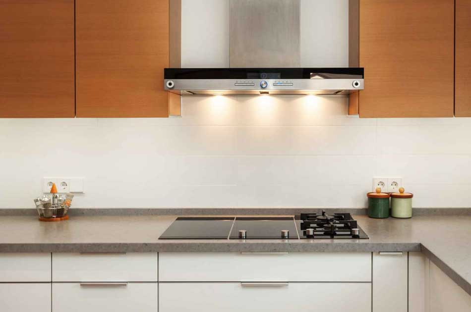 Gas cooktop and hood installed in a walnut kitchen