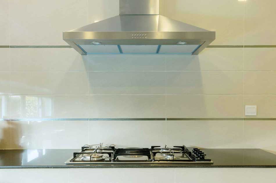 Wall-mounted stainless hood above a gas cooktop